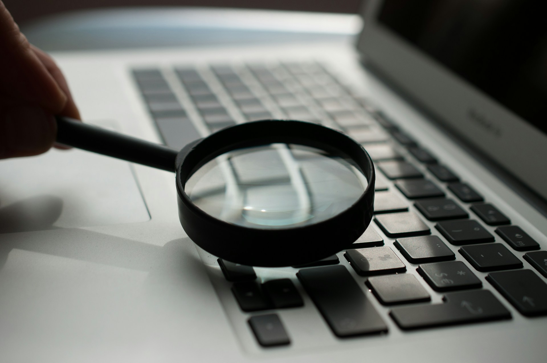 Magnifying glass over a laptop keyboard for a monthly small business IT check